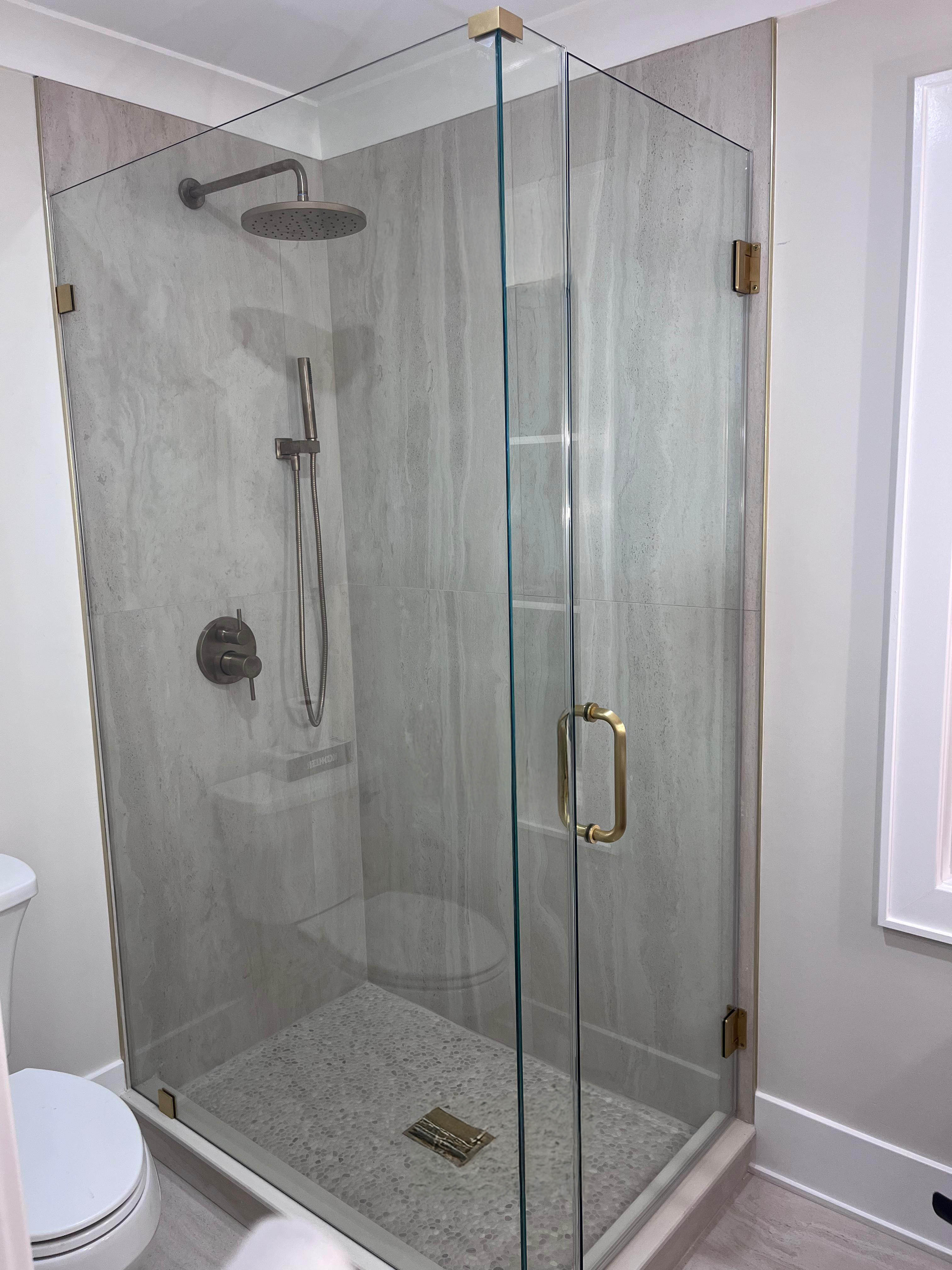 After: completed frameless corner shower enclosure with brushed gold hardware