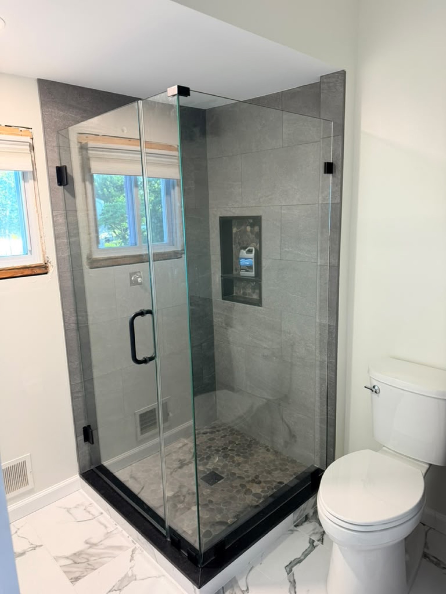 After: frameless corner shower with door, panel, and 45-degree miter return panel, matte black hardware
