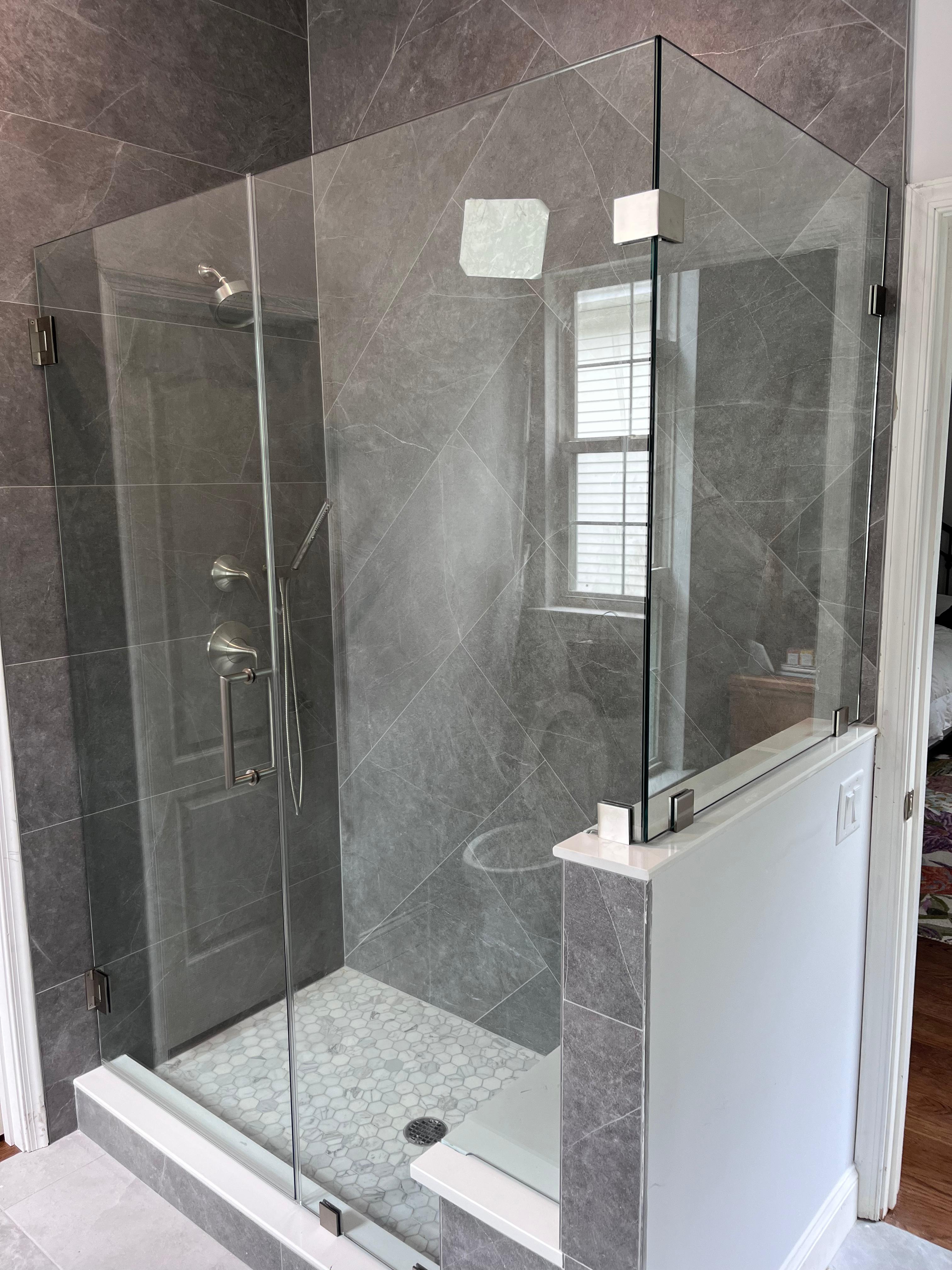 Custom frameless shower door with chrome hardware and white Calacatta marble tile