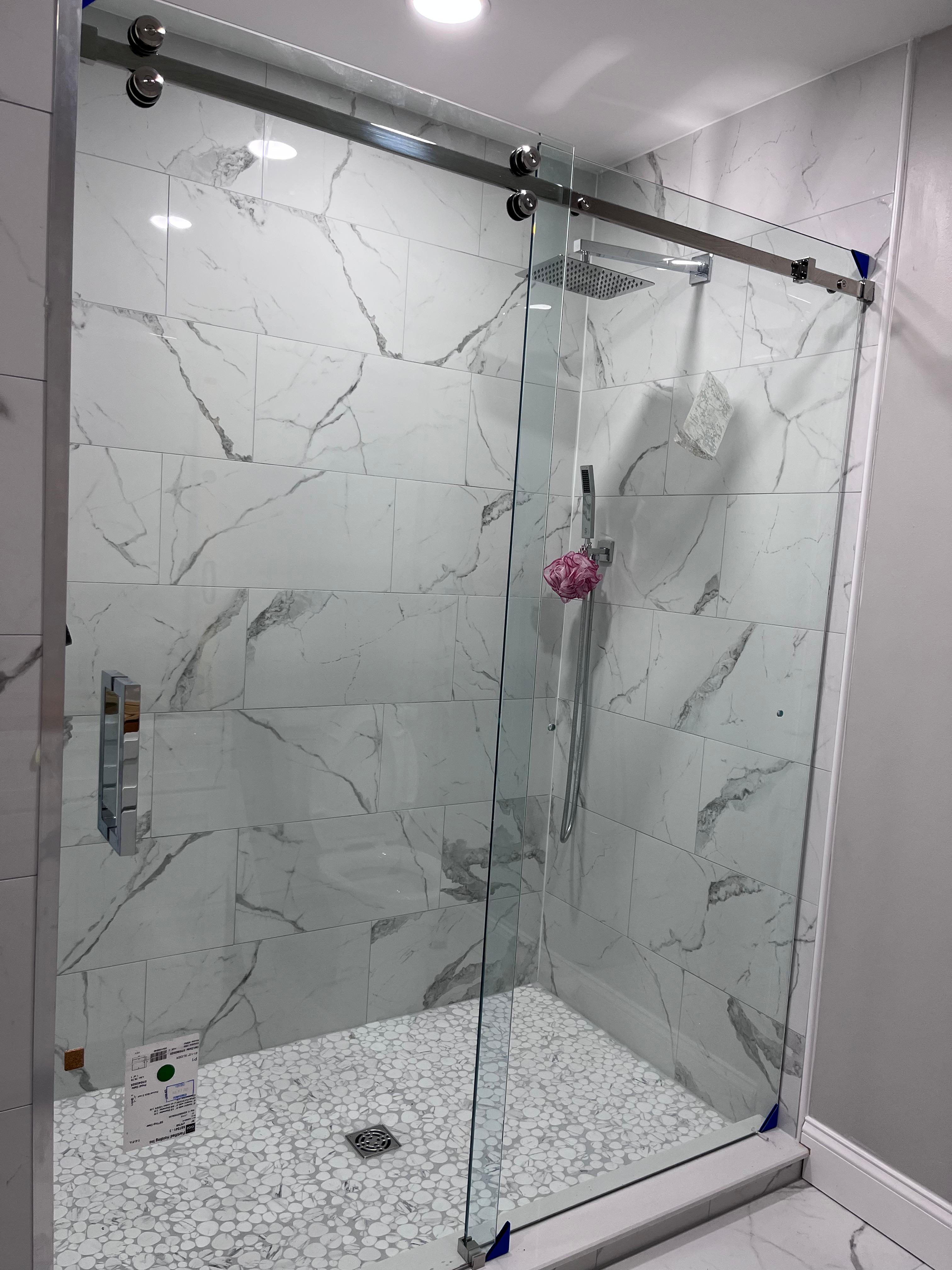 Corner frameless shower enclosure with chrome hardware and dramatic dark marble