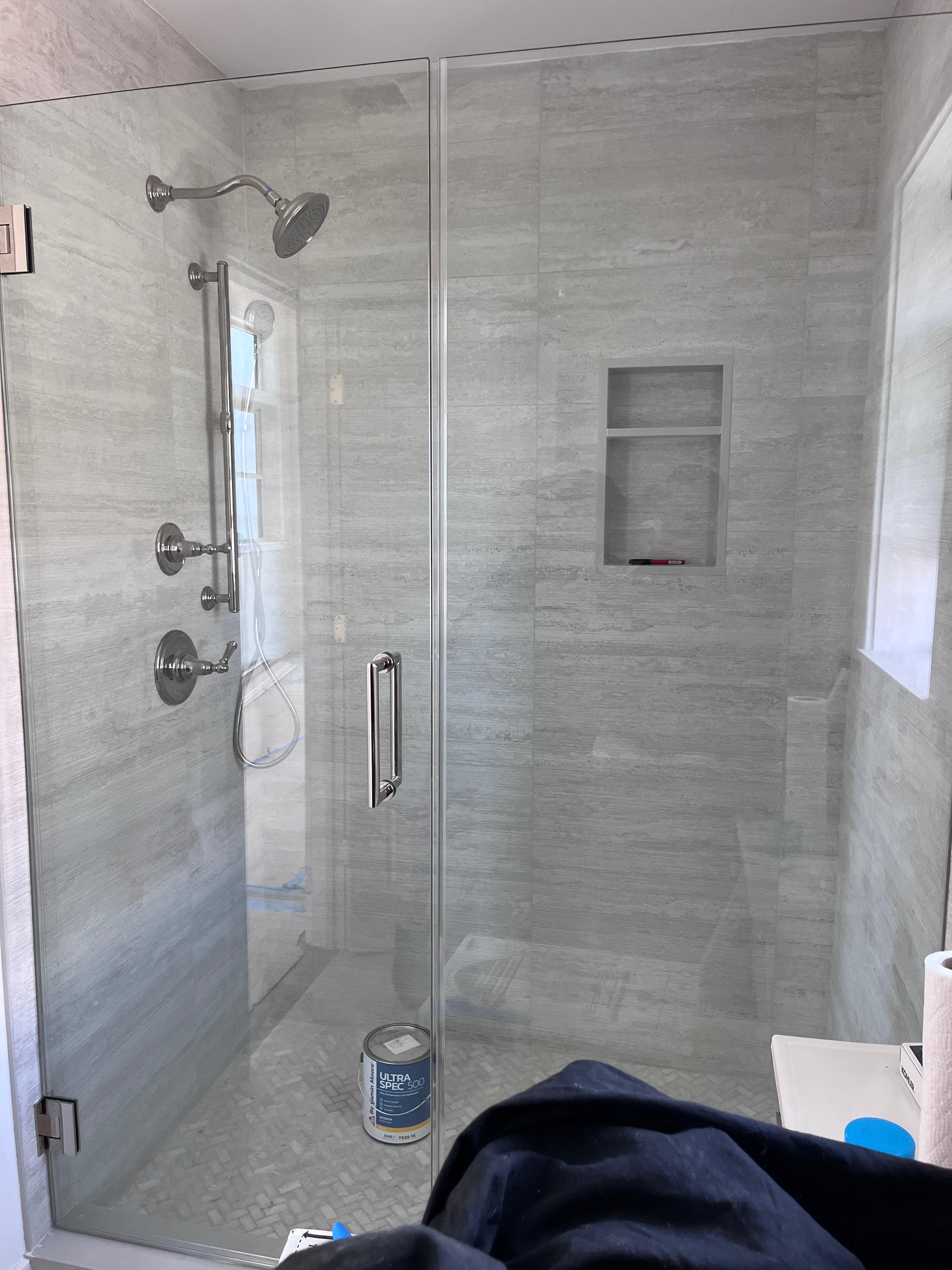 Frameless shower enclosure with brushed nickel hardware and white Calacatta marble