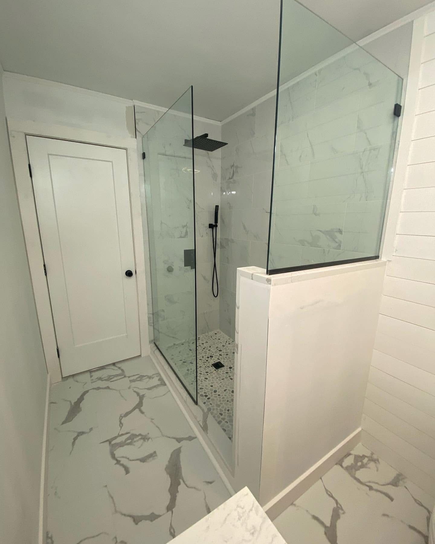 Corner frameless shower enclosure with matte black hardware alongside freestanding tub