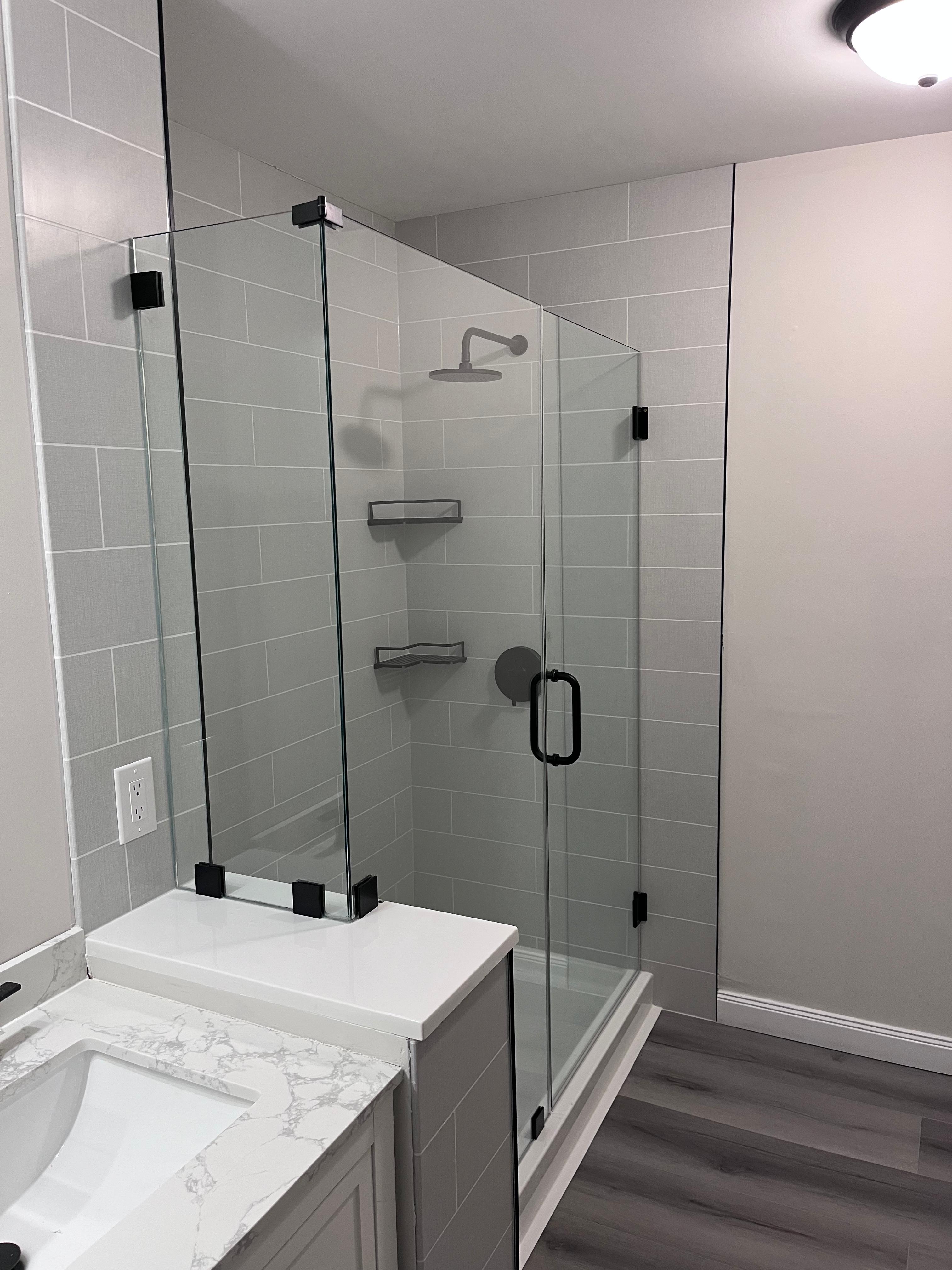 Corner frameless shower enclosure with matte black hardware on dramatic midnight marble
