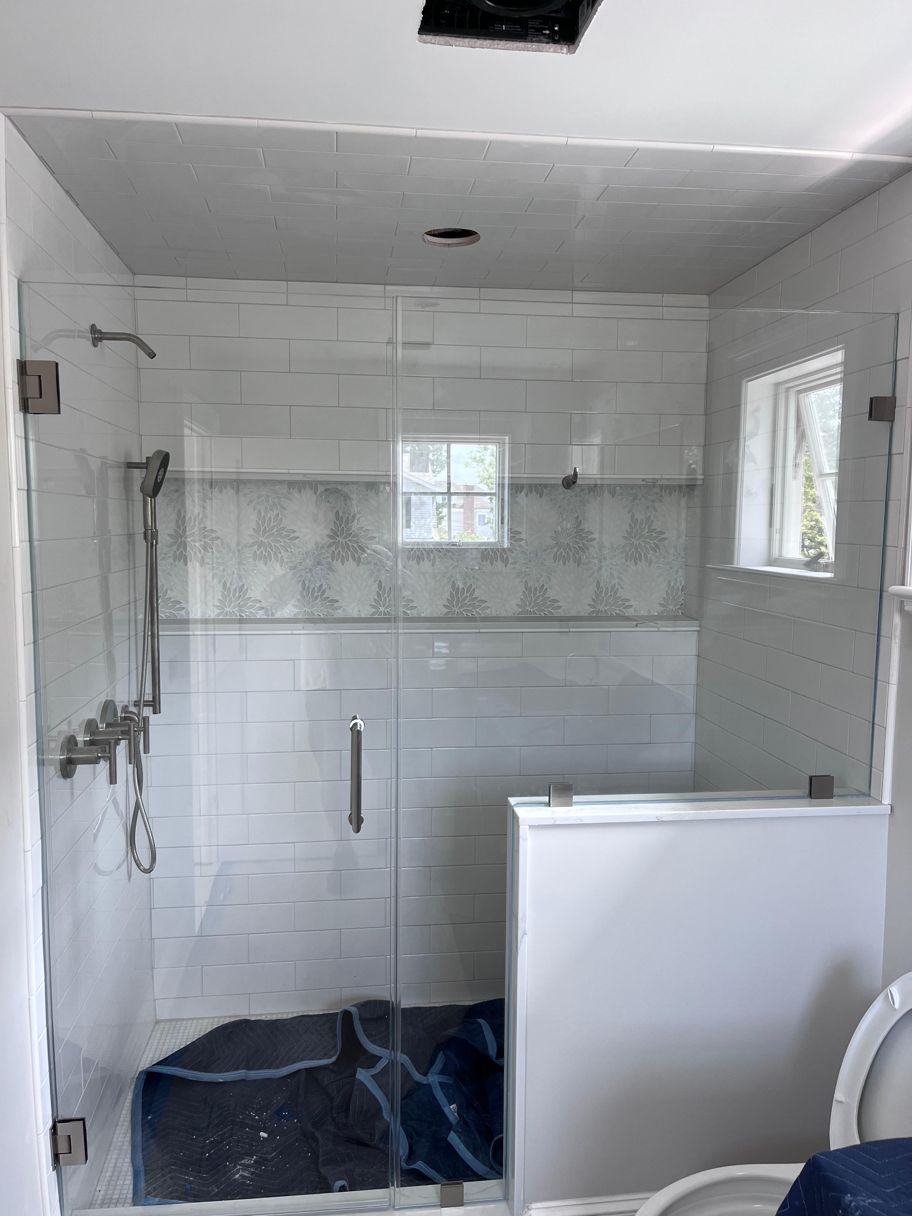 Full frameless glass shower enclosure with chrome hardware on white subway tile