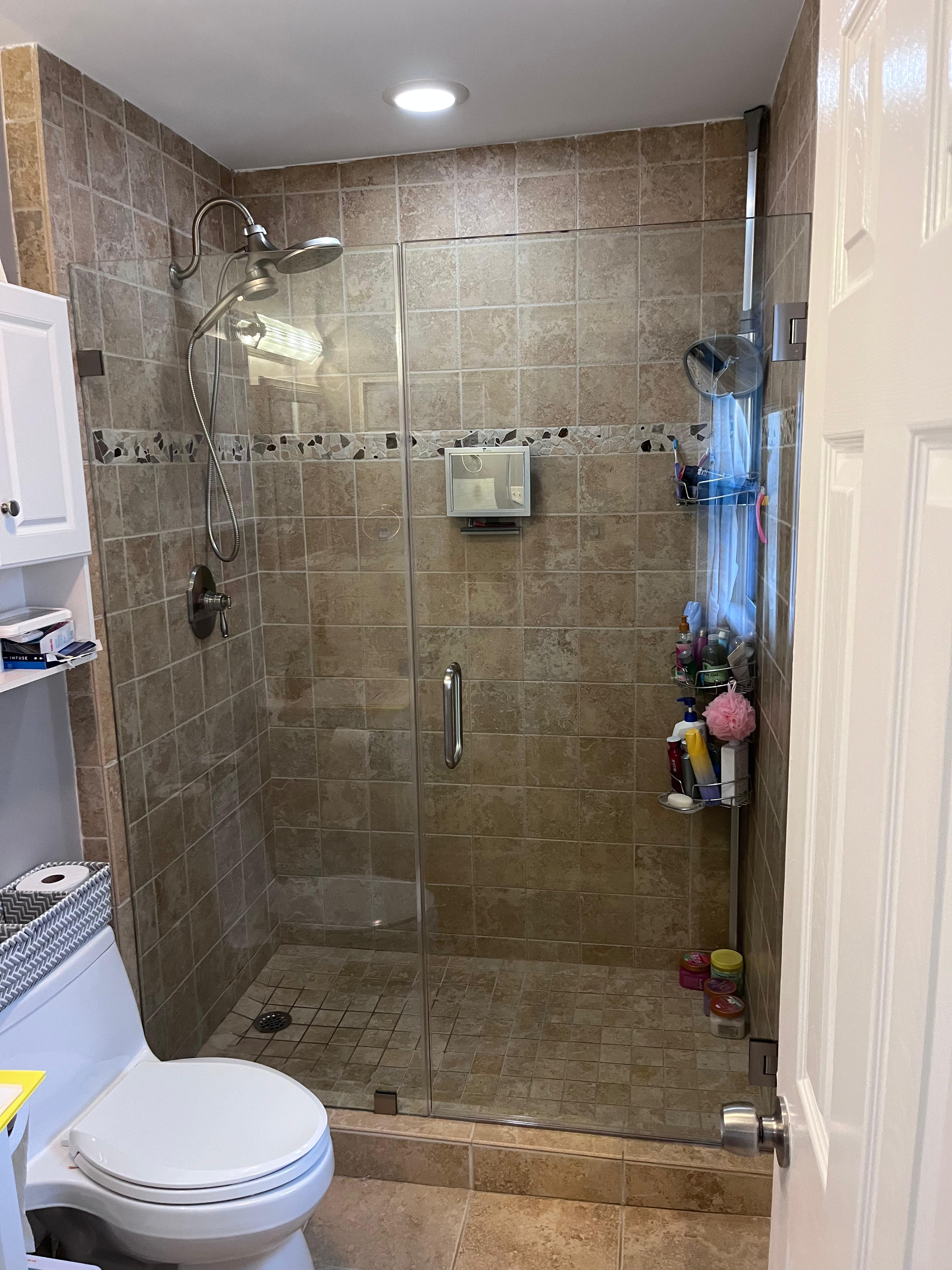 Frameless shower enclosure with brushed nickel hardware and charcoal marble tile