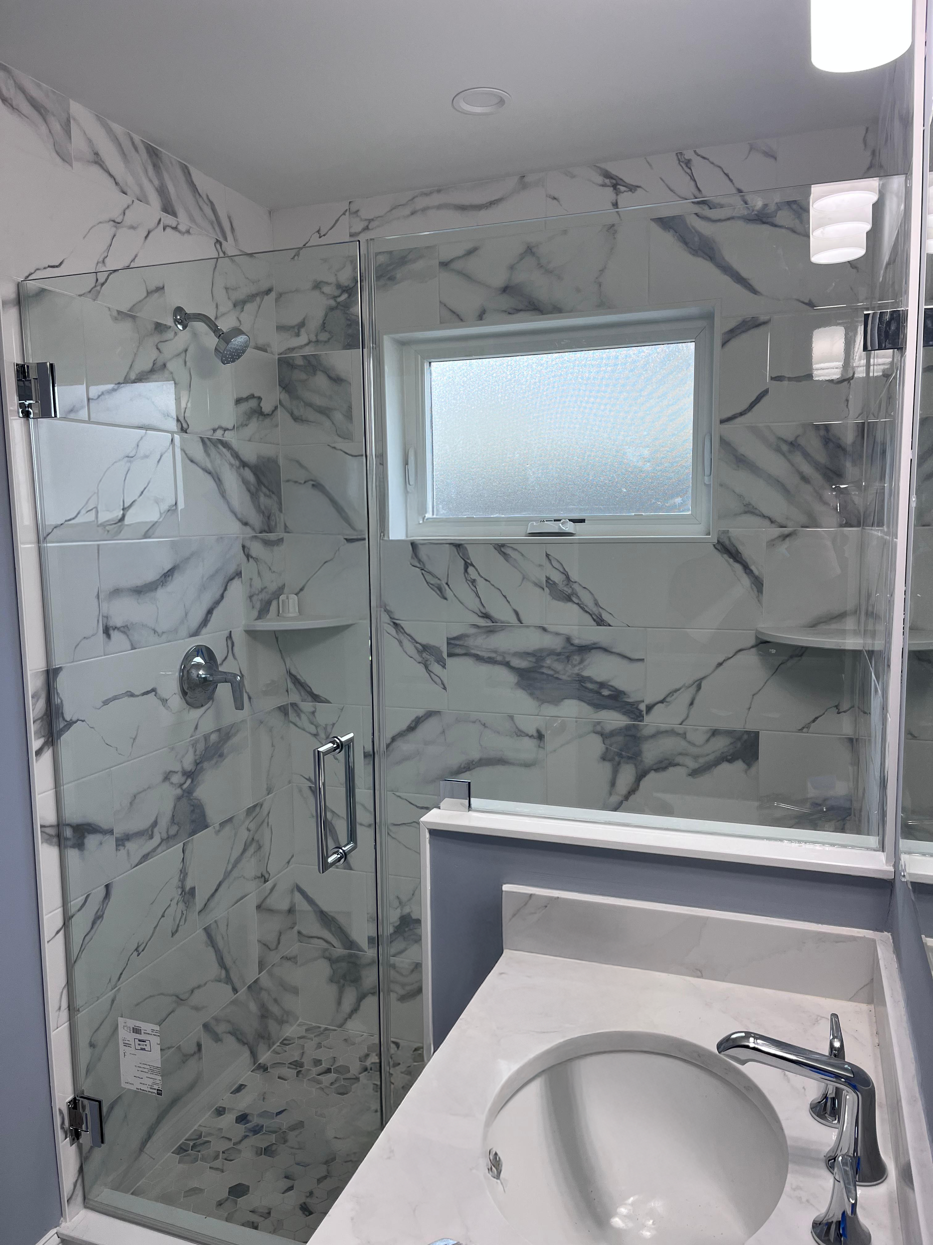 Corner frameless shower enclosure with chrome hardware on grey subway tile
