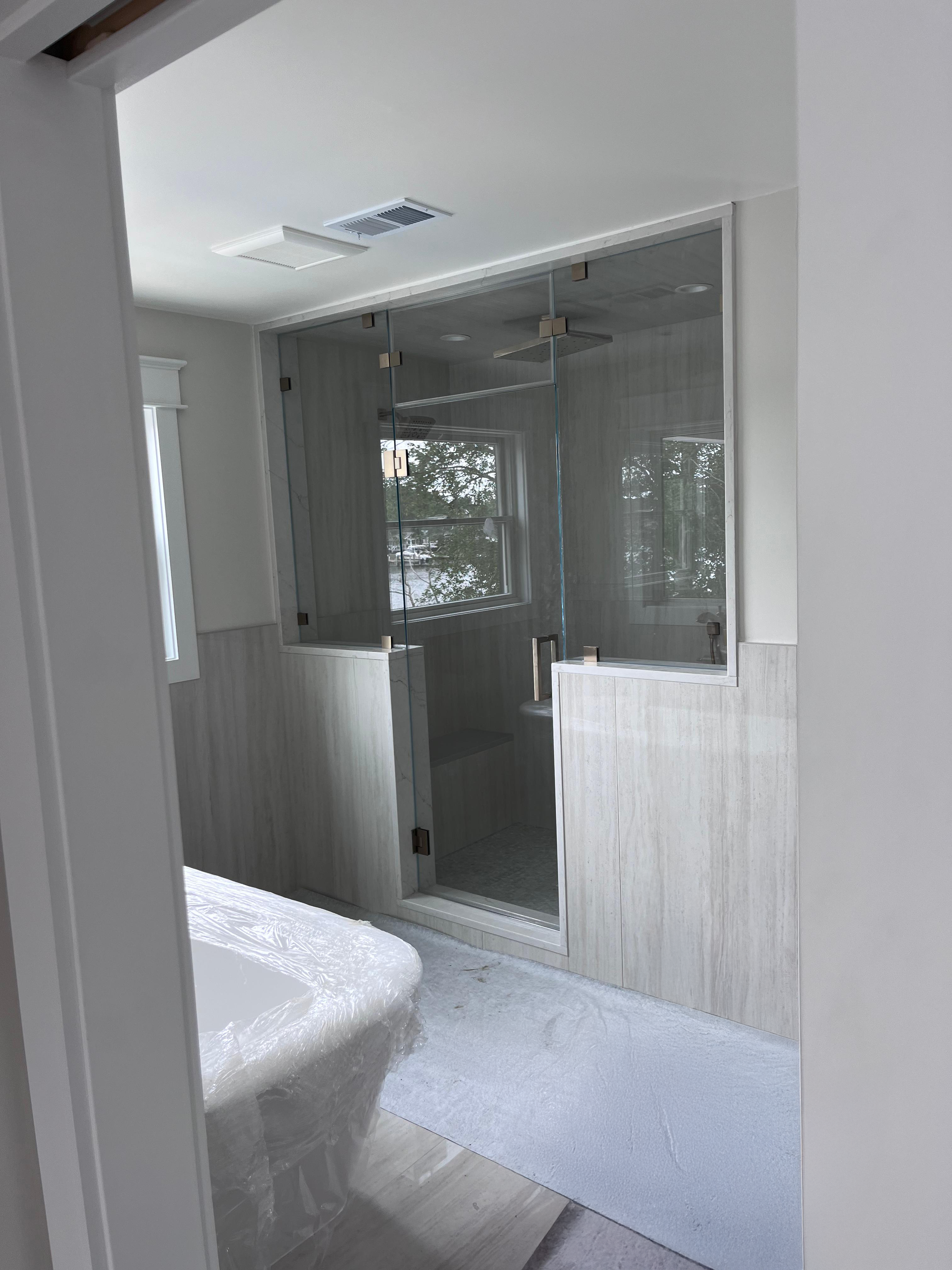 Walk-in frameless shower with door and return panel on grey linear tile