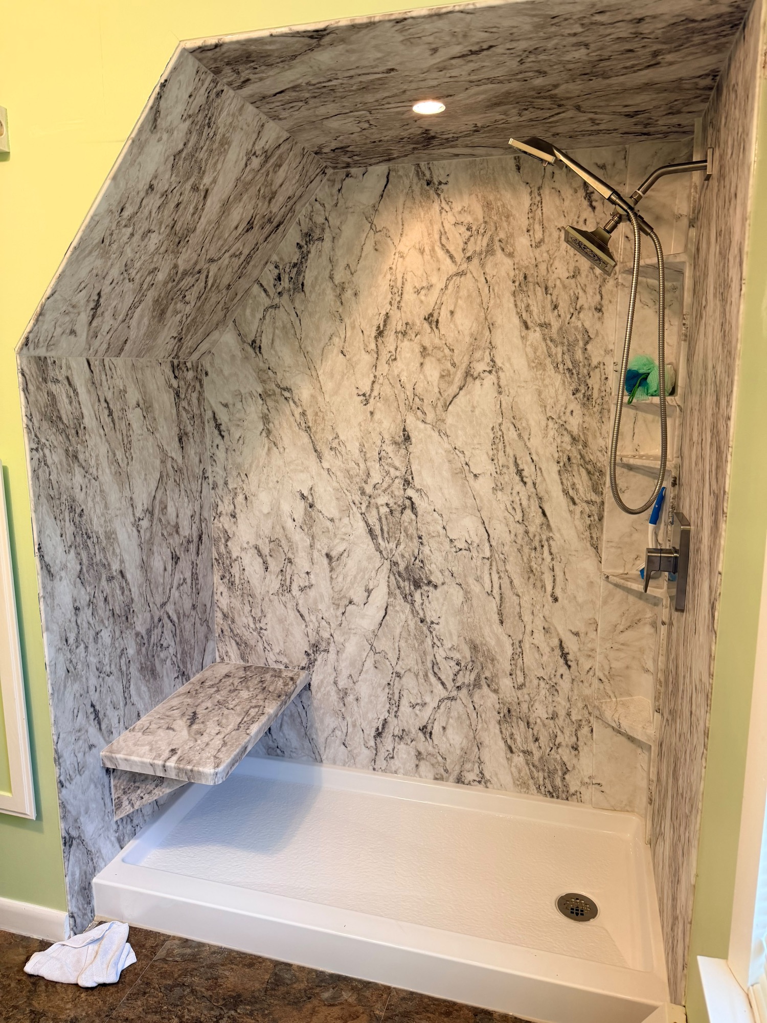 Before: marble slab shower walls with built-in bench, no glass installed