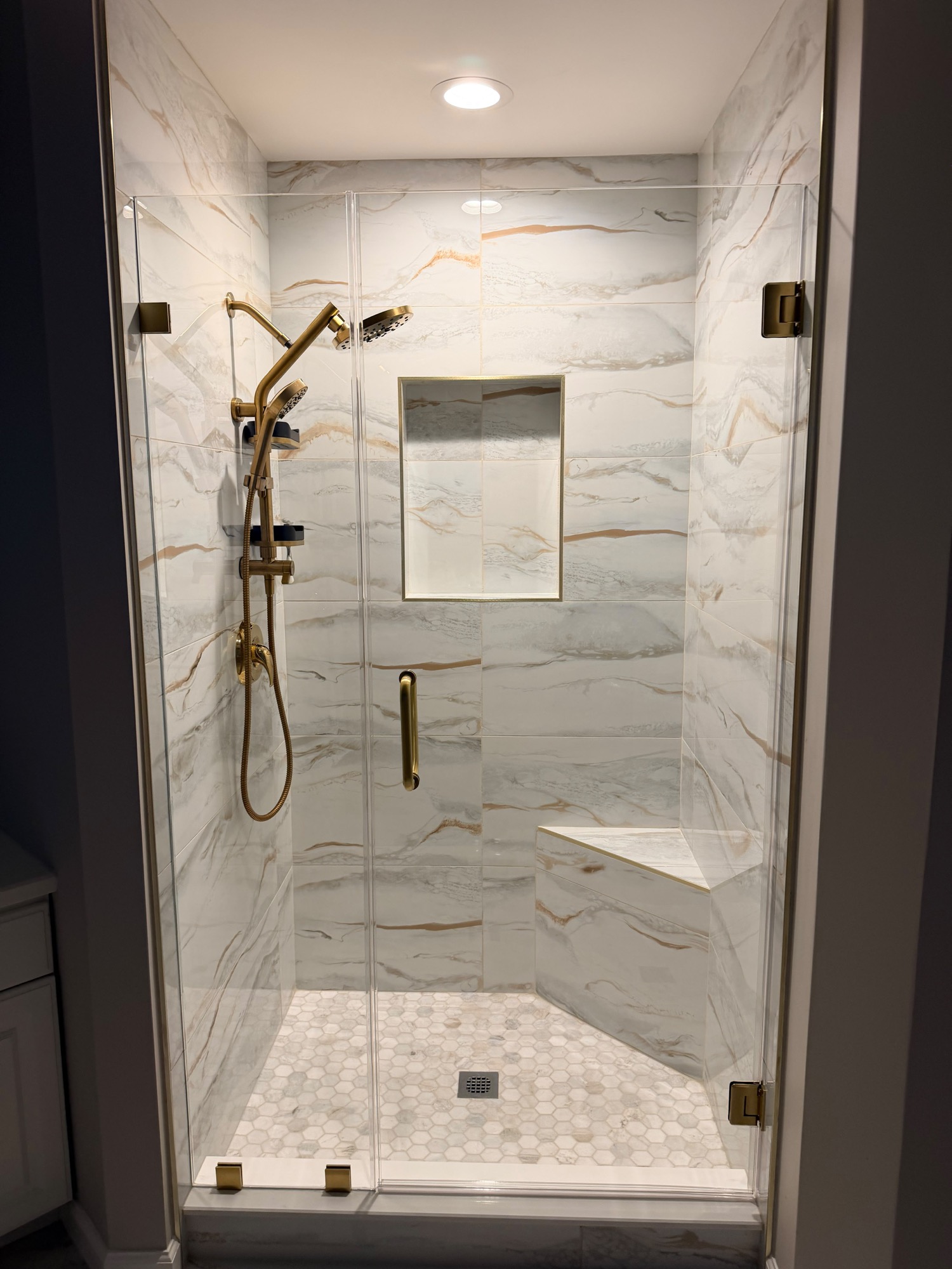 Frameless shower enclosure with marble subway tile, mosaic accent, and brushed nickel hardware
