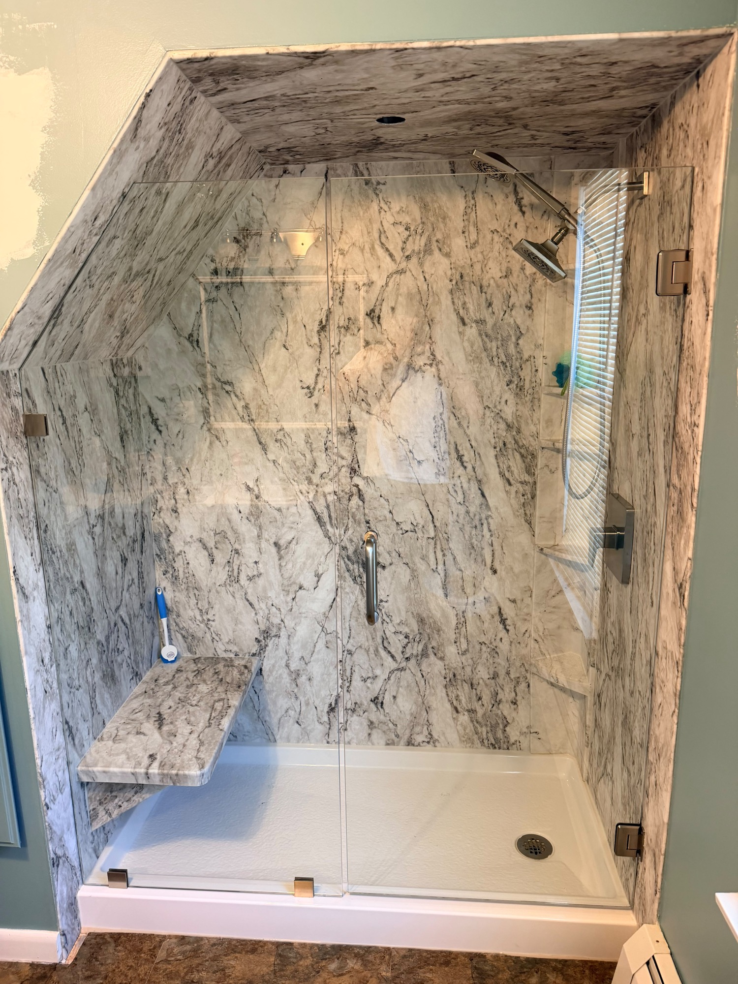After: finished marble slab shower with frameless glass door and panel