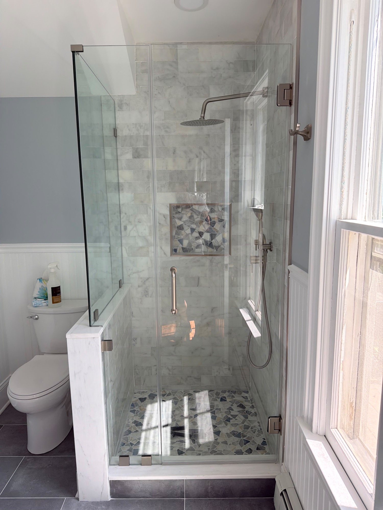 Finished custom shower with marble slab wall panels, built-in bench, and recessed lighting